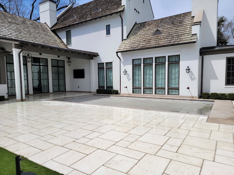 White home with paver decking surrounding pool